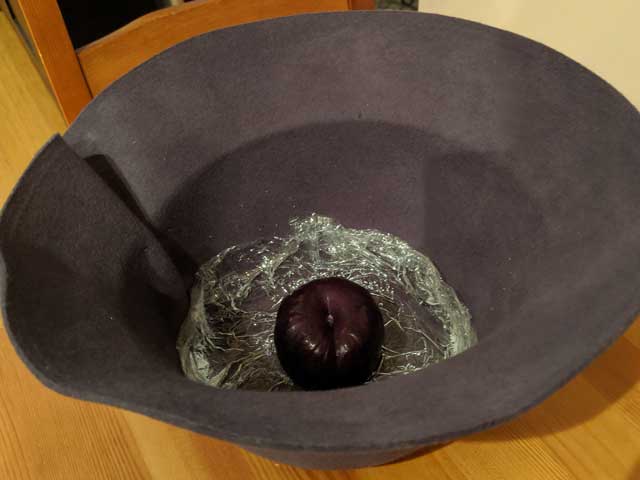 A-Single-Plum-Floating-in-Perfume-Served-in-a-Mans-Hat